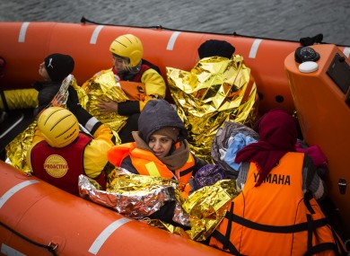 Refugees and migrants onboard a dinghy arriving to the Greek island of Lesbos yesterday