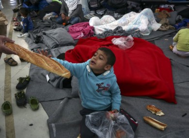 A boy is given a loaf of bread inside a passenger terminal which is used as a temporary shelter for refugees and migrants at the Athens' port of Piraeus