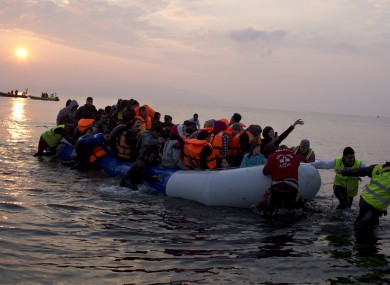 Volunteers help migrants on a dingy as they arrive at the shore of the northeastern Greek island of Lesbos.