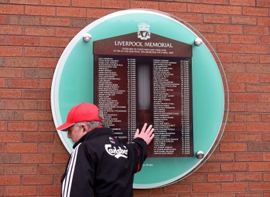 A Liverpool fan touches the Hillsborough memorial outside Anfield.
