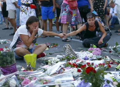 People pay tribute to the victims at the site of a deadly truck attack on the famed Promenade des Anglais in Nice, southern France.