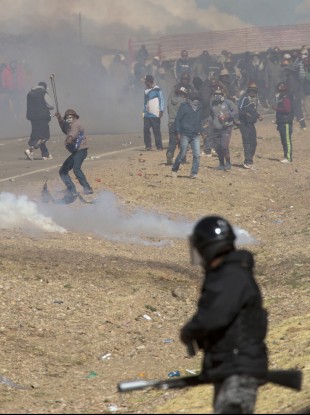 miners clash with the police as they run from clouds of tear gas during protests in Panduro, Bolivia.
