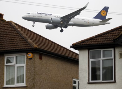 A Lufthansa plane on its final approach to landing passes over the rooftops of nearby houses at Heathrow Airport.