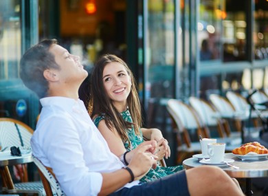 A young couple smoking outside a café in Paris.