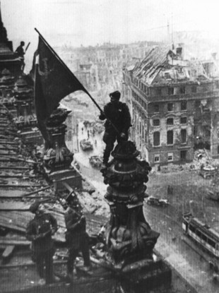 A Soviet soldier holding the national flag atop the Reichstag in Berlin in 1945