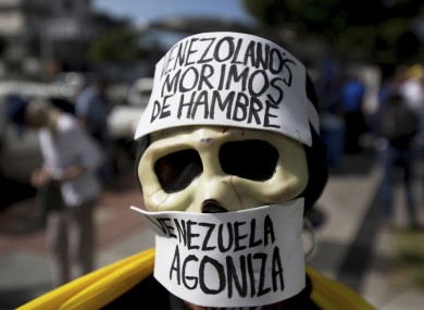 A demonstrator wears a skull mask with messages that read in Spanish: