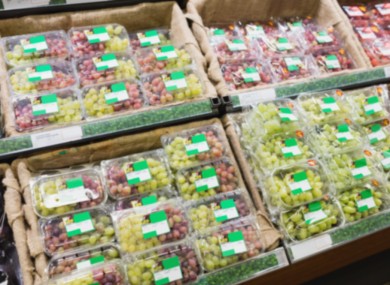 Grapes in plastic packaging on supermarket shelf.