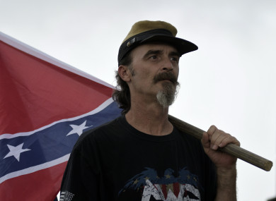 A man holds a Confederate battle flag.