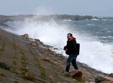 A man walking on Howth Harbour as large waves as Ex-Hurricane Ophelia battered Ireland