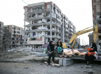 People sit at a quake site in Sarpol-E Zahab city, west of Iran