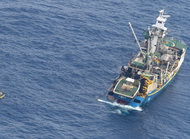 A fishing boat rescuing a dingy carrying six dehydrated adults and an unconscious baby.