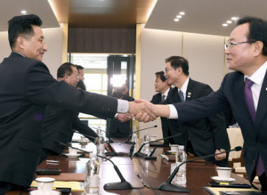 The South Korean delegation (left) and the North (right) shake hands in the Demilitarised Zone.