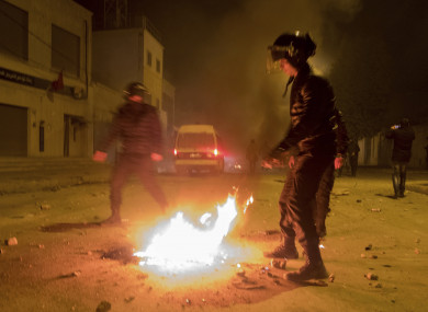 Riot police hold their positions near a fire after clashes with demonstrators in Tebourba, south of the Tunisian capital Tunis earlier this week.