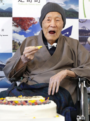 Masazou Nonaka eats a cake after receiving a certificate from Guinness World Records