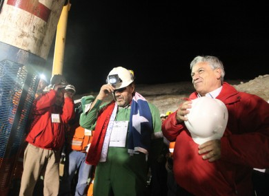 Luis Urzua, the final miner released, stands with president Sebastian Pinera as workers sing the Chilean national anthem.