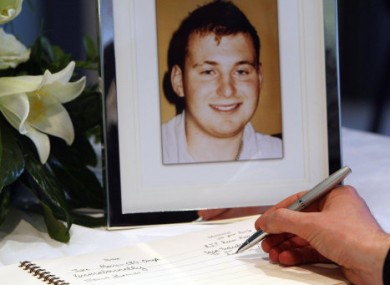A man signs a book of condolences for Ronan Kerr, pictured.