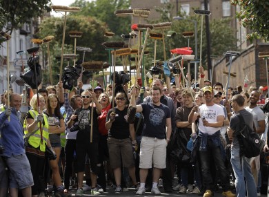 London residents wait to be allowed through a police cordon to help council workers with the clear up after the rioting that took place last night outside Clapham Junction railway station