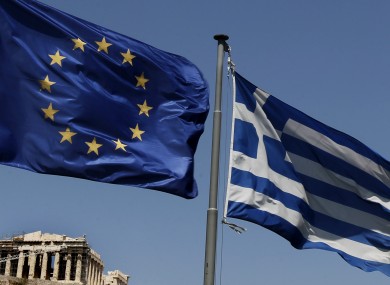 A European Union left and the Greek flag wave above the ancient Parthenon temple, at the Acropolis Hill, in Athens.