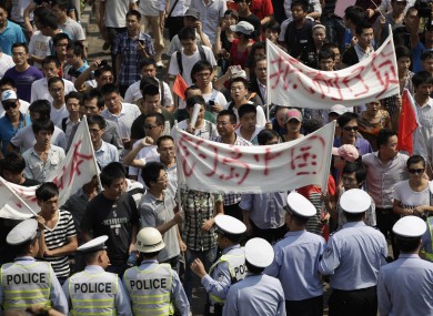 Police officers stop anti-Japan protesters marching through street in Shanghai, China.