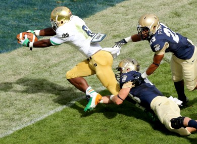 Notre Dame's running back Theo Riddick scores the opening touchdown despite Keegan Wetzel and Chris Ferguson of the Navy.