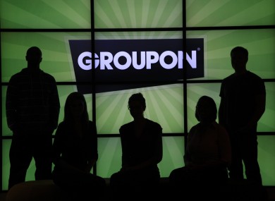 File: Employees at Groupon pose in silhouette by the company logo in the lobby of the online coupon company's Chicago offices.