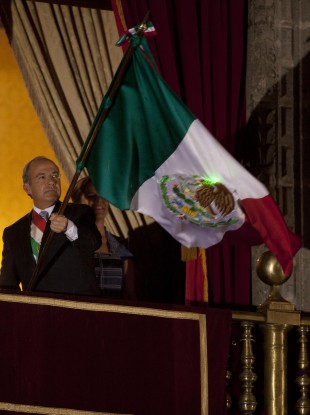 Felipe Calderon with the flag of Mexico or the United Mexican States as it's officially known, for now.