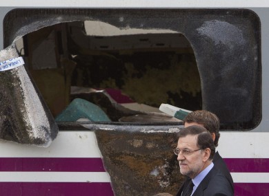 Spanish prime minister Mariano Rajoy walks next to a derailed car at the site of a train accident.