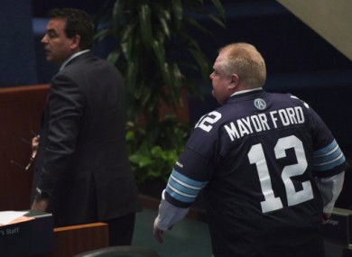Ford chairs a meeting of Toronto City Council wearing a jersey of the local CFL franchise, the Toronto Argonauts. The team chided him for wearing the jersey.