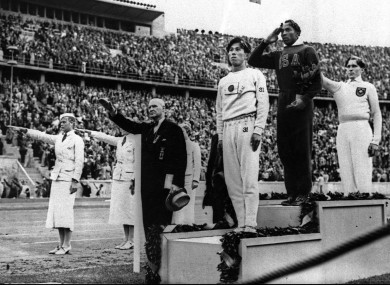 Jesse Owens salutes during the medal ceremony after he won Gold for the long jump. Germany's Lutz Long (right) gives the Nazi salute.