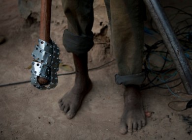 A young neighborhood resident carries makeshift weapons.