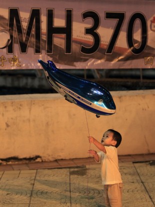A boy plays with an aeroplane shaped foil balloon during a candlelight vigil for passengers aboard the missing Malaysia Airlines Flight MH370, in Kuala Lumpur.