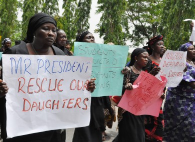 Mothers of the students hold signs calling for them to be rescued