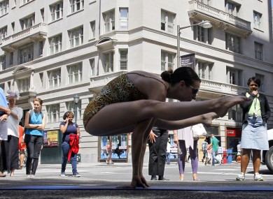 Thayne Dibble, an instructor with Bikram Yoga demonstrates yoga poses as people look on a corner of Rittenhouse Square.