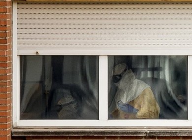 Medical practitioners wearing protective clothing are seen attending a patient inside an isolated ward on the sixth floor of the the Carlos III hospital in Madrid.