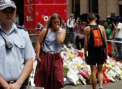 A woman cries after laying a flower at a makeshift memorial in Sydney.