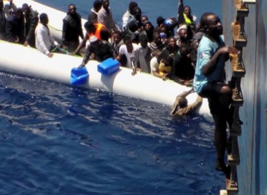 Migrants on a sinking rubber boat desperately being rescued in the Mediterranean Sea.