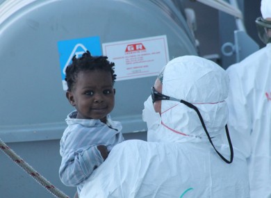 A member of the LÉ Samuel Beckett crew holds a young girl rescued off the coast of Tripoli.