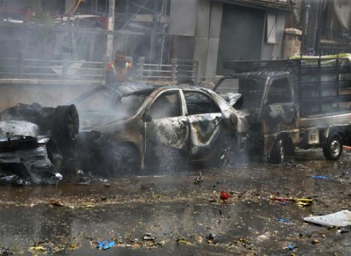 In this photo released by the Syrian official news agency SANA, a firefighter tries to extinguish a fire at the scene where one of rockets hit the Dubeet hospital in the central neighbourhood of Muhafaza in Aleppo.