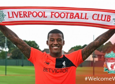 Wijnaldum holds up the Liverpool scarf at Melwood today.