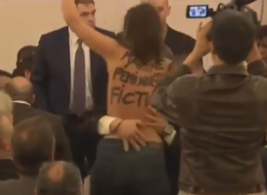 The topless activist was removed from the press event by security.