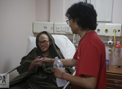 A family member gives water to Taiwanese man Liang Sheng-yueh at the Grande Hospital in Kathmandu, Nepal.