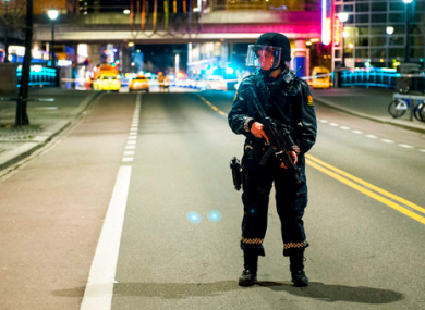 An officer stands guard as police cordon off a large area around a subway station on a busy commercial street.
