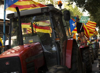 A woman with the estelada, or Catalonia independence flags, shouts slogans on top of parked tractors during a protest by farmers in Barcelona today.