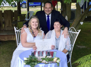 Lainey Carmichael, left, Roz Kitschke, right, and celebrant Jason Betts pose as they show Lainey and Roz's marriage certificate at their home in Franklin, south of Hobart, Australia.