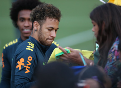 Brazil's Neymar (L) signs for fans after a training session of the Brazilian national soccer team.