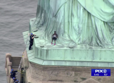 Police officers climbed up on a ladder to stand on a ledge nearby talking the climber into descending in New York