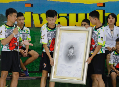 The boys making their first public appearance, holding a photo of the volunteer diver who died during their rescue.