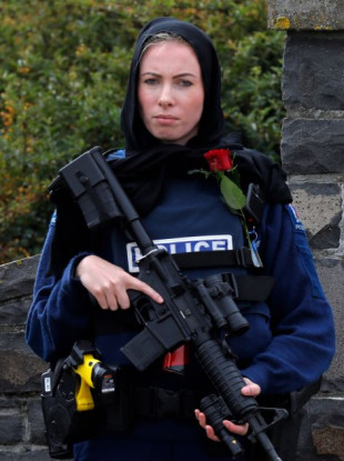 A police officer standing guard outside Memorial Park Cemetery in Christchurch while a burial of one of the victims took place today.