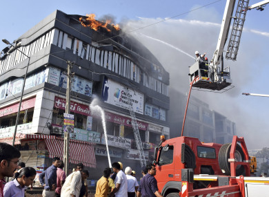 Firefighters work to douse flames on a building in Surat.