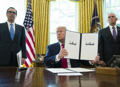 President Donald Trump holds up a signed executive order to increase sanctions on Iran.
